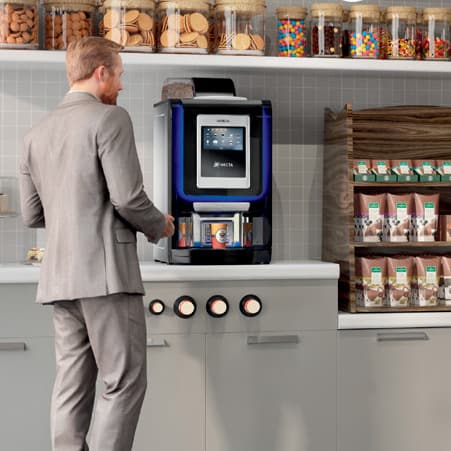 A Business man in the office canteen making a coffee on a rented coffee machine 