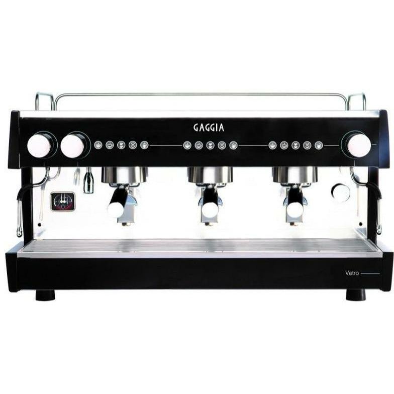 "Close-up image of a sleek Gaggia Vetro 3 Espresso machine, featuring a polished stainless steel deck with black panels on the exterior, a group head for coffee extraction, and a touch control panel of hardened glass with buttons for various brewing options."